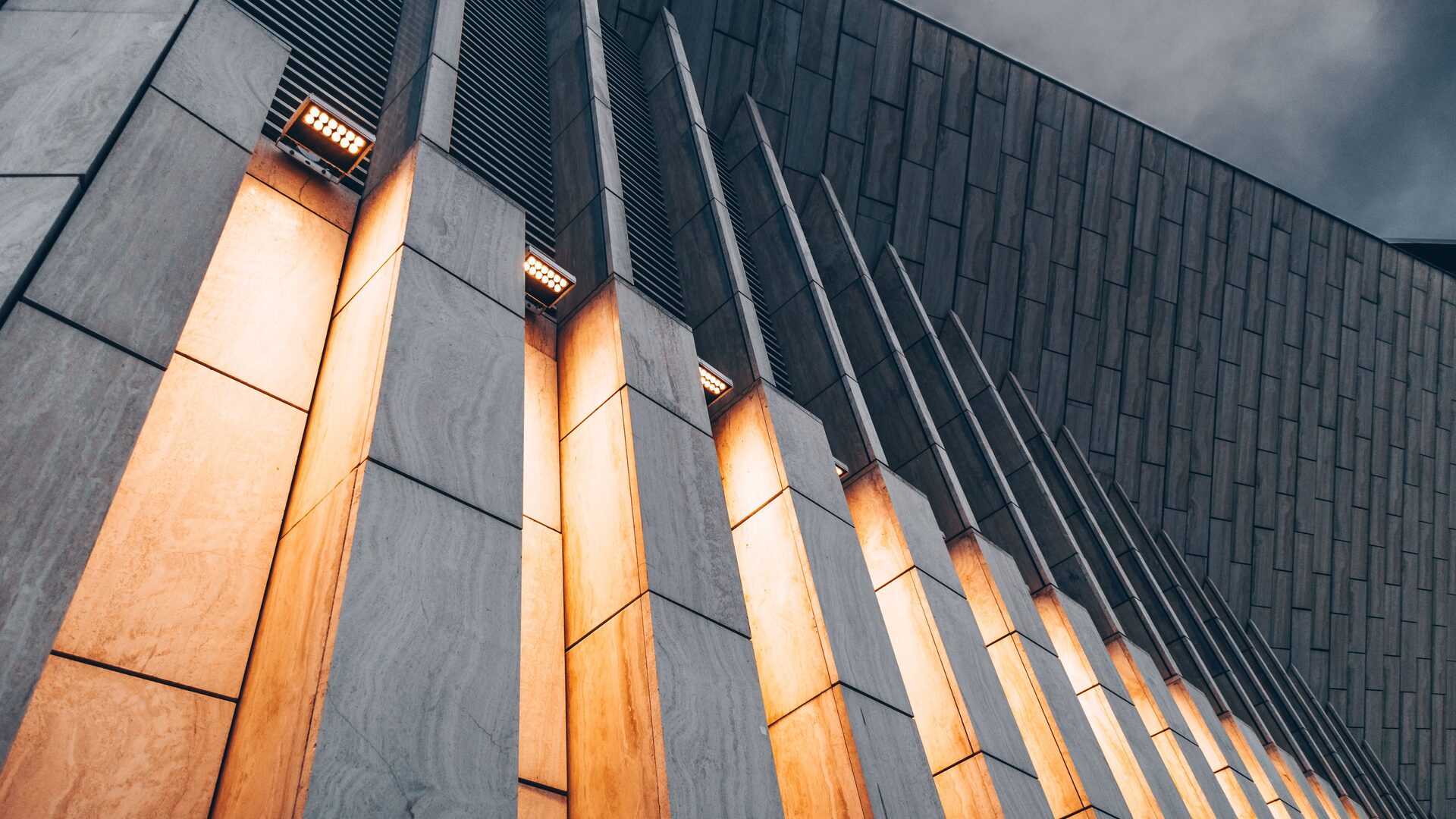 Modern building facade with warm gold light between dark stone pillars
