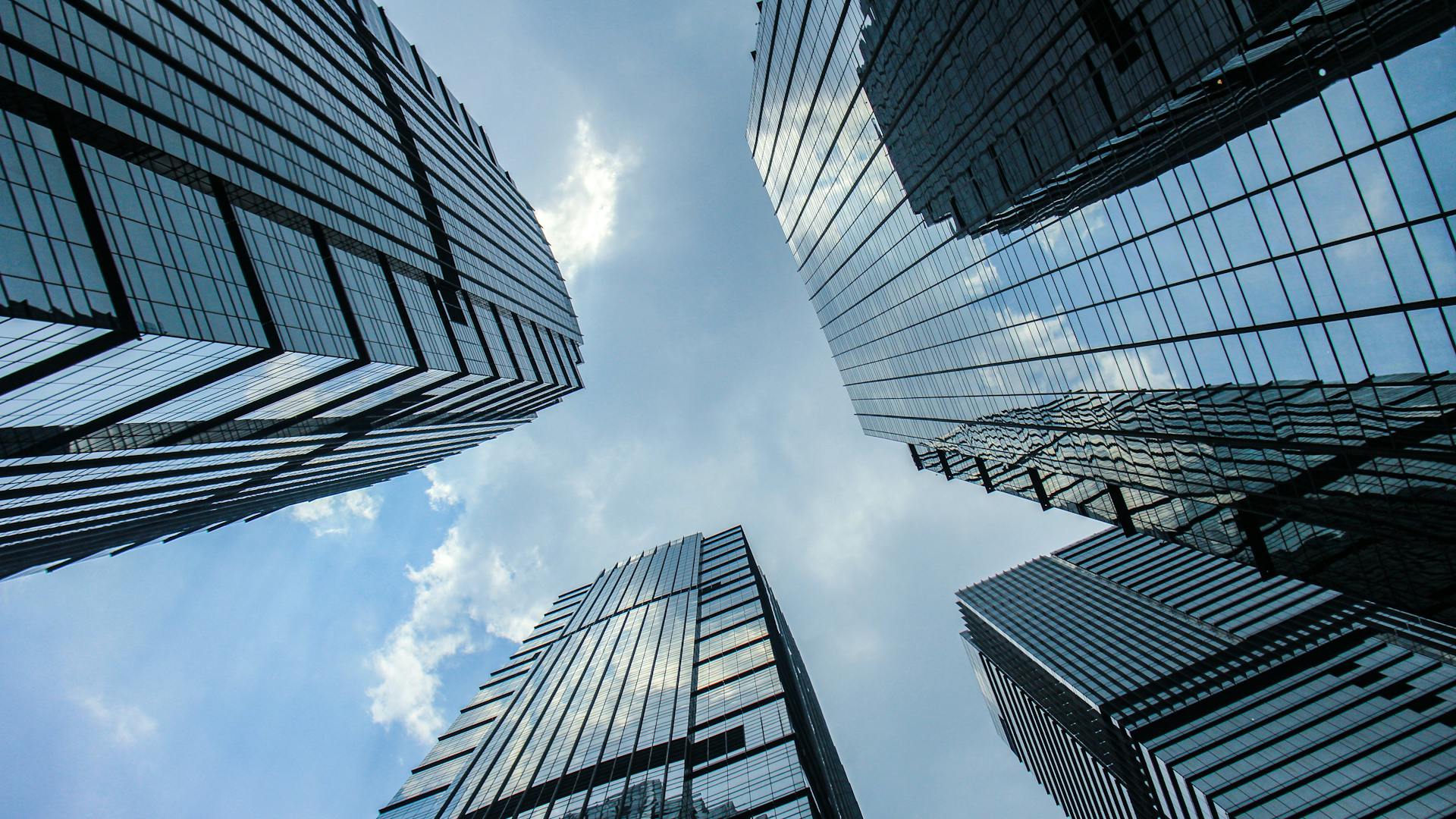 Looking up at modern glass skyscrapers converging toward the sky